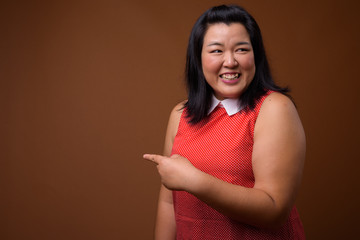 Obraz premium Beautiful overweight woman laughing and pointing finger to copy space