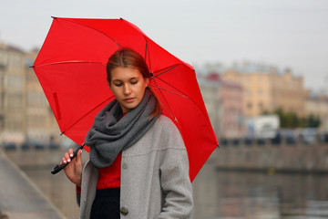 Girl with a red umbrella on the background of the city channel