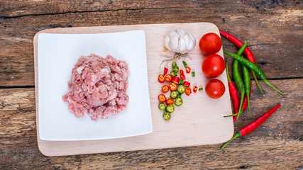 meat with vegetables and spices on wooden background