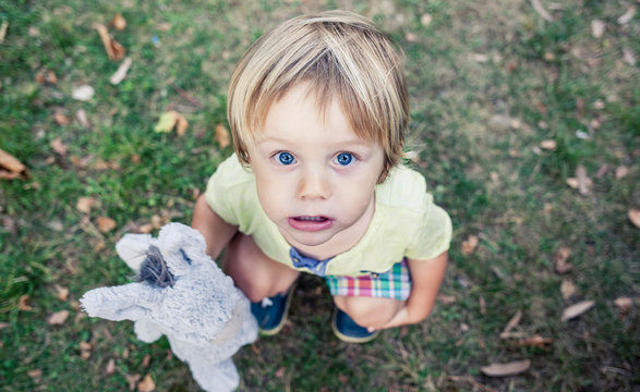 ni&ntilde;o agachado con peluche en la mano mirando hacia arriba