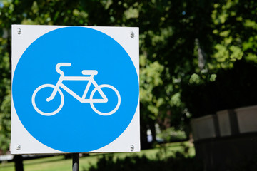 Signs of bicycle parking on background of green trees in park. Copy space.