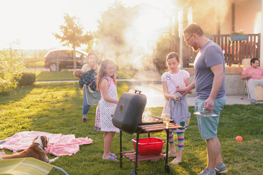 Picture of big happy family making barbeque in their backyard. Family time on sunny summer day.