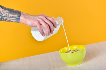 milk pouring into a yellow cup with granola