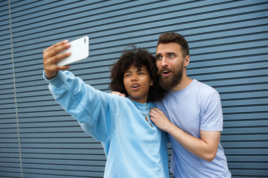 girl and hipster guy taking selfie on a street