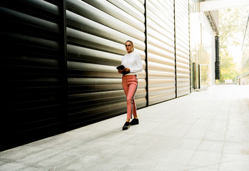 Pretty young woman with digital tablet by the office building