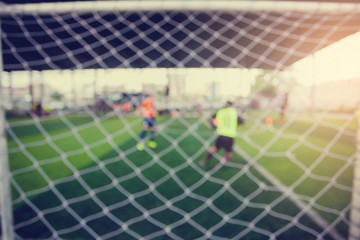 Mesh of goal with blurry football player.