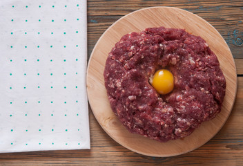 Raw minced meat and other ingredients on cutting board