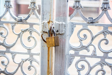 Key lock, gold lock, white steel door with curved rusty pattern.