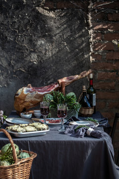 Tablecloth setting with artichokes, red wine and jam serrano leg