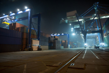 industrial port with containers. Stack of containers, gantry crane at night. Industrial Container...