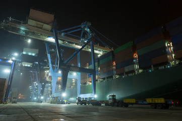 Container ship in port at container terminal in night. container ships stand in terminal of port on loading, unloading container. Sea port Cotnainer terminal.