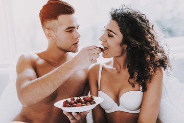 Happy Romantic Couple Eating Strawberrys in Bed