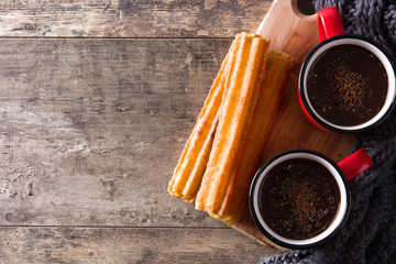 Hot chocolate with churros on wooden table. Top view. Copyspace

