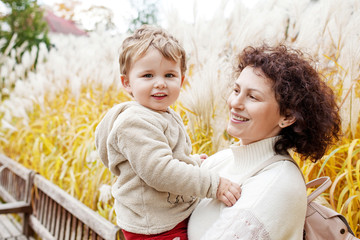 Happy mother and her little child. Smiling child playing with mother in the park. Mother and son embracing.