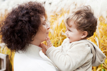 Happy mother and her little child. Smiling child playing with mother in the park. Mother and son embracing.