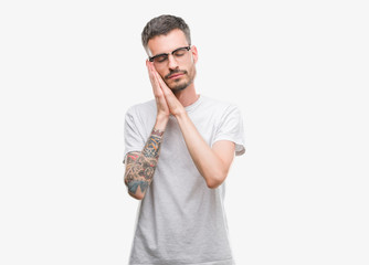 Young tattooed adult man sleeping tired dreaming and posing with hands together while smiling with closed eyes.