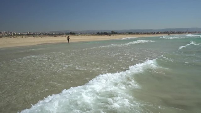 Clear skies and water, while standing in the ocean, person walking in the background