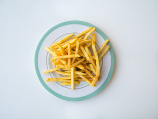 Fried French fries on a plate on a white table.