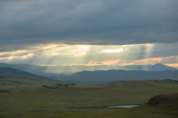 Sunset over the mountain landscape. A beautiful sun rays with clouds. Republic Of Khakassia, Russia.