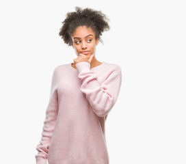Young afro american woman wearing winter sweater over isolated background looking confident at the camera with smile with crossed arms and hand raised on chin. Thinking positive.