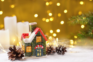 Decoration of the New Year's table in the form of a clay house, white candles with sparkling garlands on a golden background