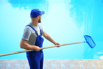Male worker cleaning outdoor pool with scoop net