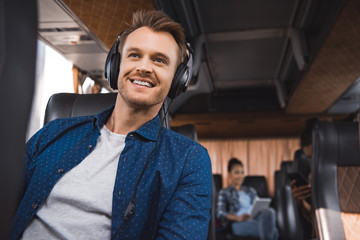 cheerful man in headphones listening music during trip on travel bus