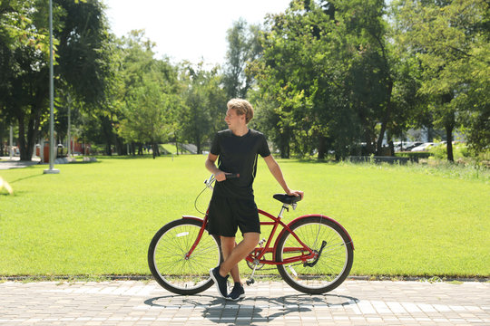 Attractive man with bike outdoors on sunny day