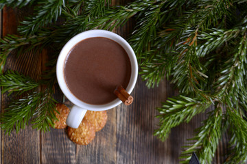 Obraz na płótnie Canvas Hot chocolate or cocoa with cinnamon stick in a cup and fir branches. Winter hot drink for cold weather. New year and Christmas concept Top view