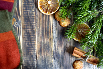 Obraz na płótnie Canvas Christmas and new year background frame or postcard Christmas composition with fir branches dried oranges cookies cinnamon sticks and a scarf on a wooden background