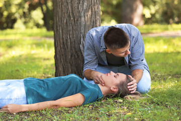 Naklejka na ściany i meble Man checking for breathing of unconscious woman outdoors. First aid