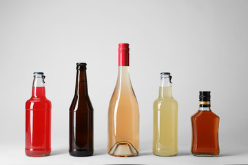 Bottles with different alcoholic drinks on light background