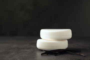 Soap bars and vanilla pods on grey table. Space for text