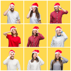 Collage of group of young people wearing christmas hat over yellow isolated background doing ok gesture with hand smiling, eye looking through fingers with happy face.