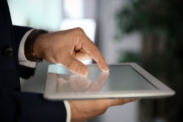 Businessman using digital tablet at workplace, closeup of hand. Mockup for design
