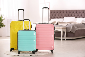 Colorful suitcases packed for journey in bedroom. Space for text
