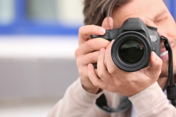 Naklejka premium Male photographer with professional camera on blurred background. Space for text