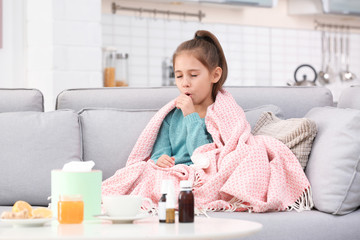 Little girl suffering from cough and cold on sofa at home