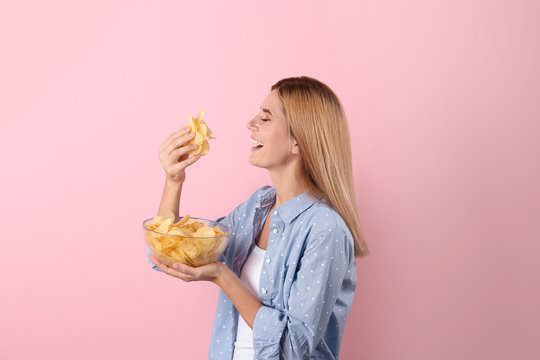 Woman eating potato chips on color background