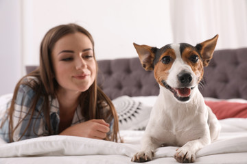 Beautiful woman with her dog lying in bed at home