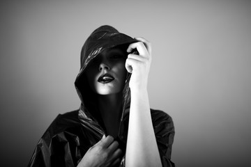 Emotive photo of a beautiful bald woman in a black raincoat with the hoods on.
