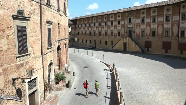 View of Bishop's Seminary with tourists in San Miniato, Tuscany, Italy. Hikers walking in front of Episcopal building. Travelling along Via Francigena. Red bricks and fresco painting 18th Century