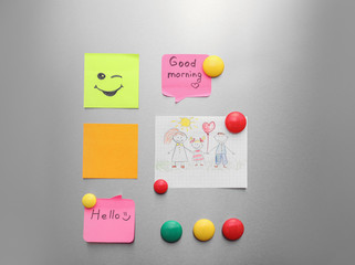 Paper sheets, child's drawing and magnets on refrigerator door