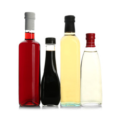 Bottles with different kinds of vinegar on white background