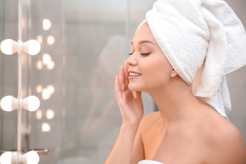 Beautiful woman with towel on head in bathroom