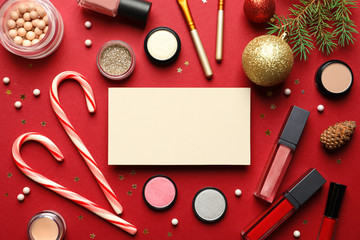 Flat lay composition with makeup products, empty card for design and Christmas decor on background