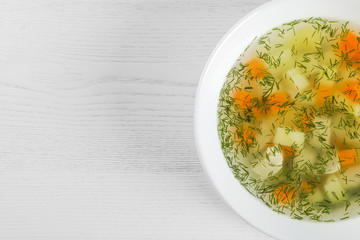Bowl of fresh homemade soup to cure flu on wooden background, top view with space for text