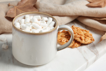 Cup of hot cozy drink, tasty cookies and  autumn leaves on table