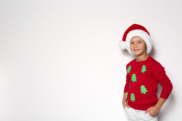 Cute little boy in handmade Christmas sweater and hat on white background. Space for text