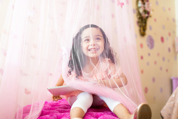 Offspring With Tablet Computer Sitting Under Drapes